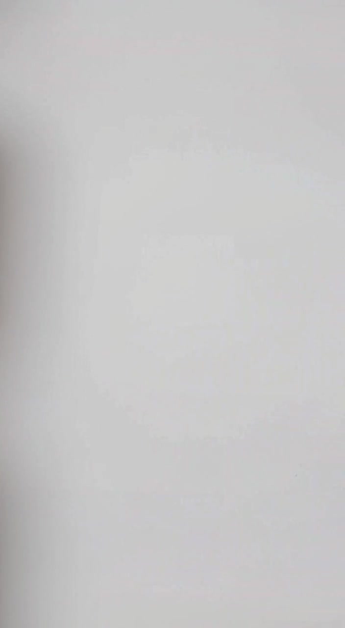 The young man slowly nods his head while maintaining a confident smile against the simple white wall.