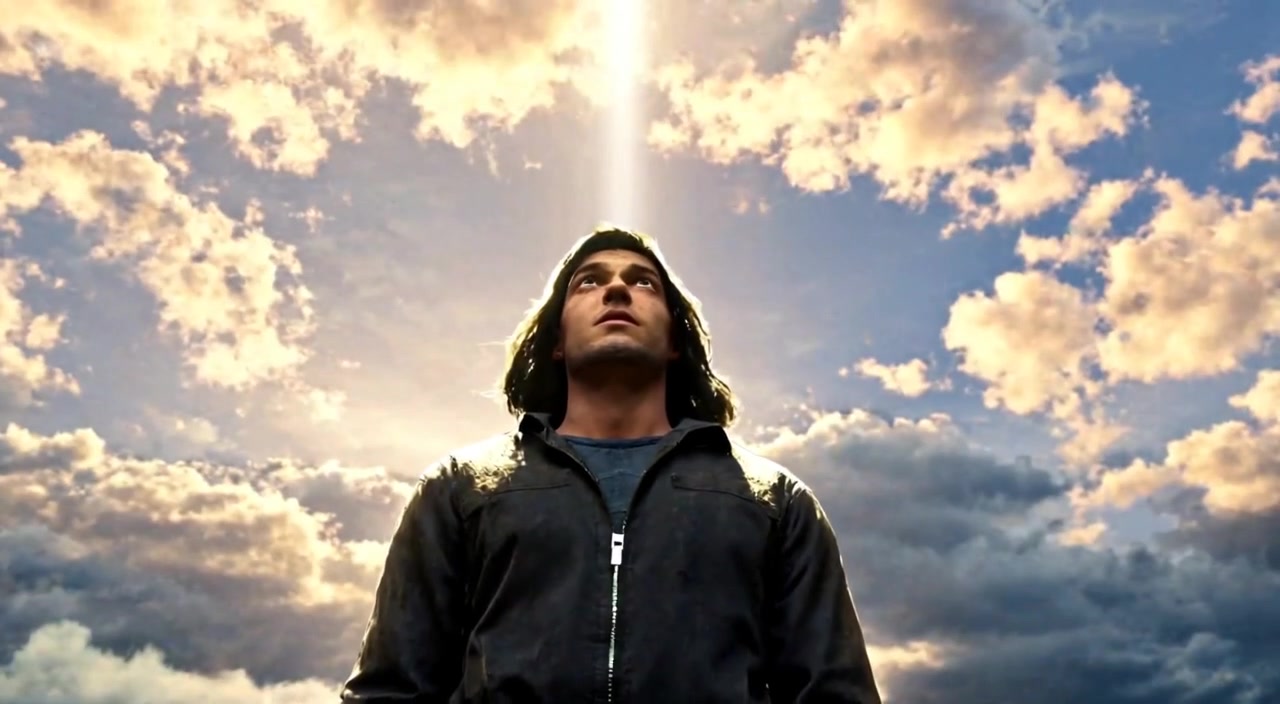 A bright sunbeam breaks through the clouds, illuminating Kael's face as he gazes upwards in awe.