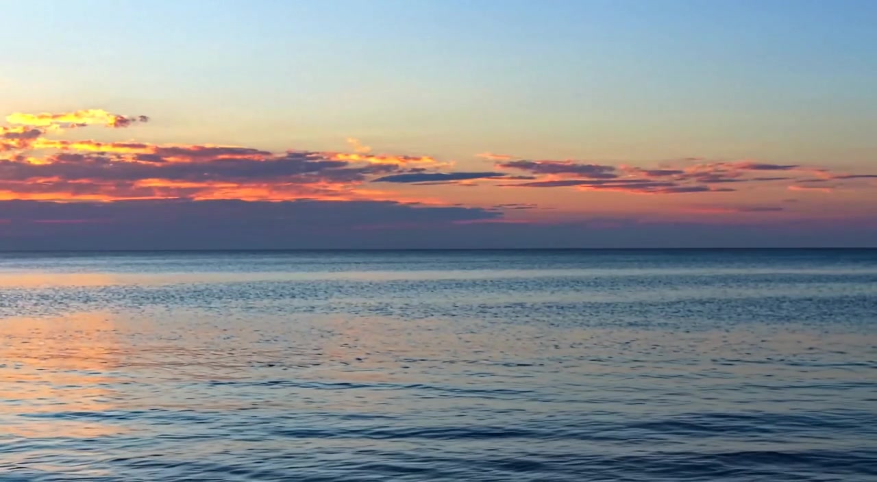 The man gazes towards the horizon as gentle ripples flow on the river, illuminated by soft morning sunlight.