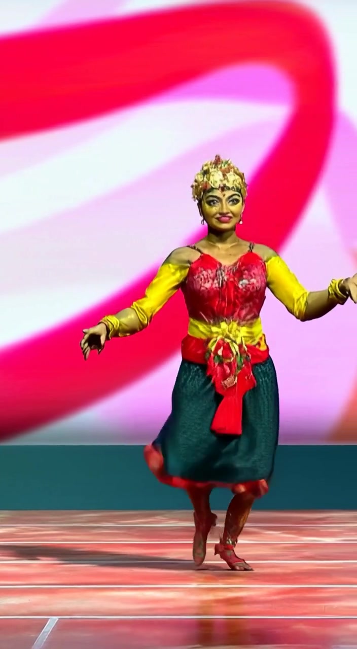 The dancer gracefully twirls on stage, colorful costumes flowing while shadows dance in the background.