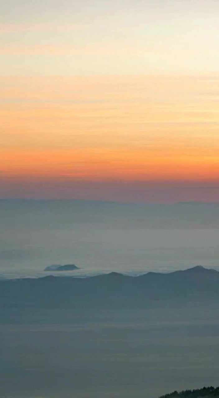 The man gazes into the horizon as the soft light of dawn bathes the landscape.