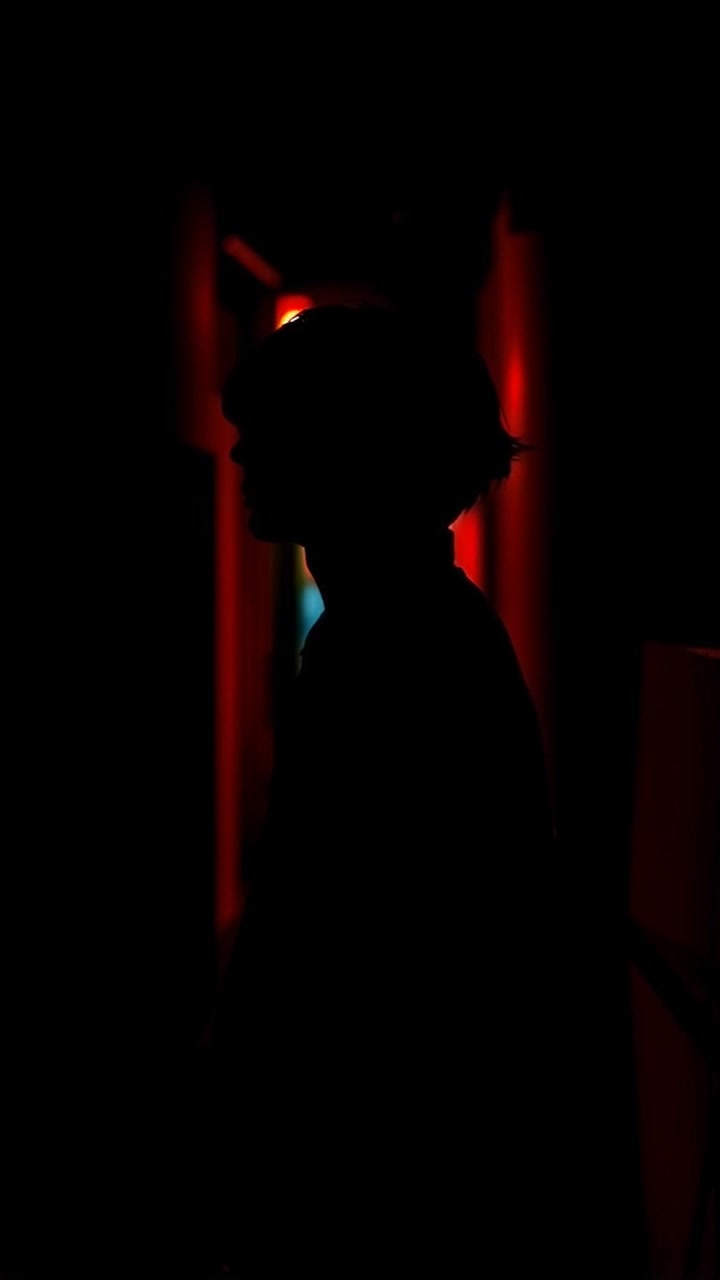 Kaito stands in a dark alley, shadows looming over him.