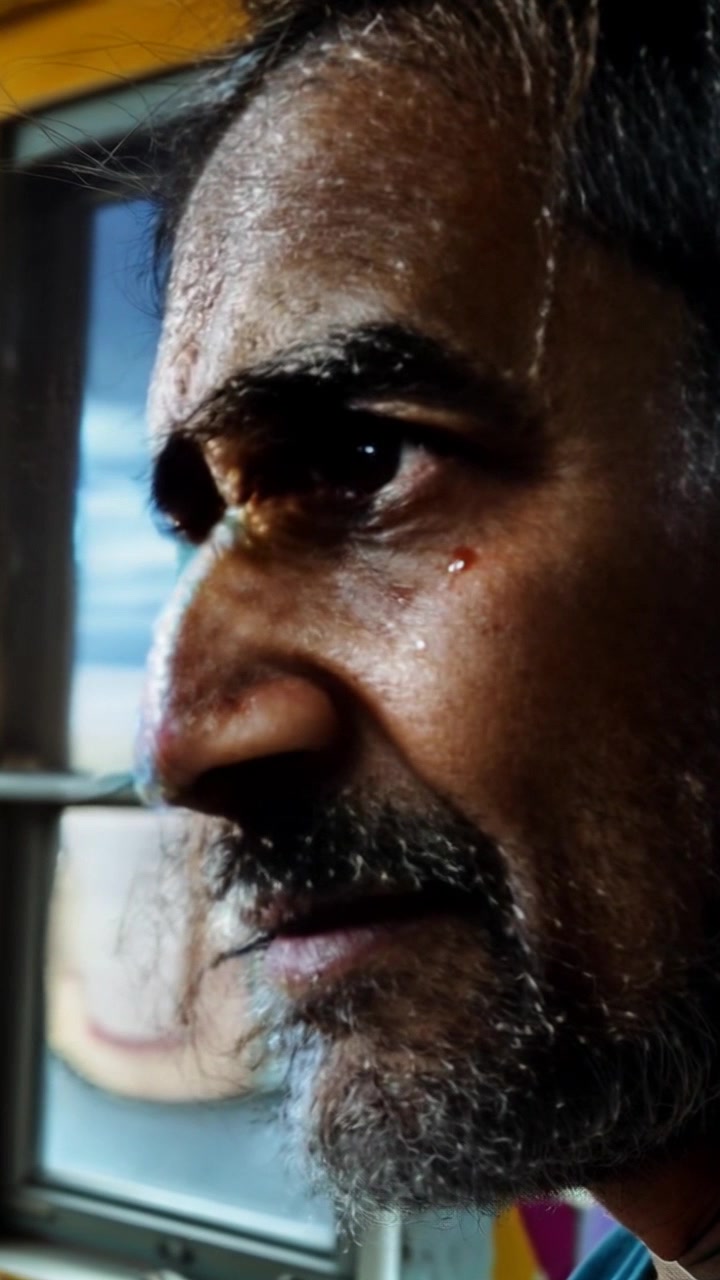 Scene: A close-up of a person's face, filled with despair and contemplation, against a backdrop of a gloomy sky visible through a window. Style: Moody, soft lighting that captures the nuances of emotion on the subject's face and the gray tones of the sky. Motion: The camera gently pushes in for an intimate view, slowly capturing the contours of the face as a single tear glistens, offering a poignant glimpse into the subject's inner turmoil.
